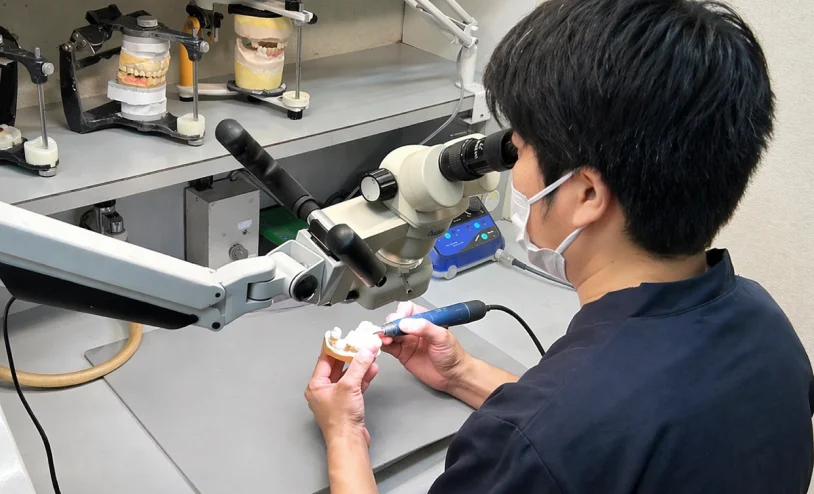 歯科技工士が顕微鏡を使って補綴物を精密に加工している様子